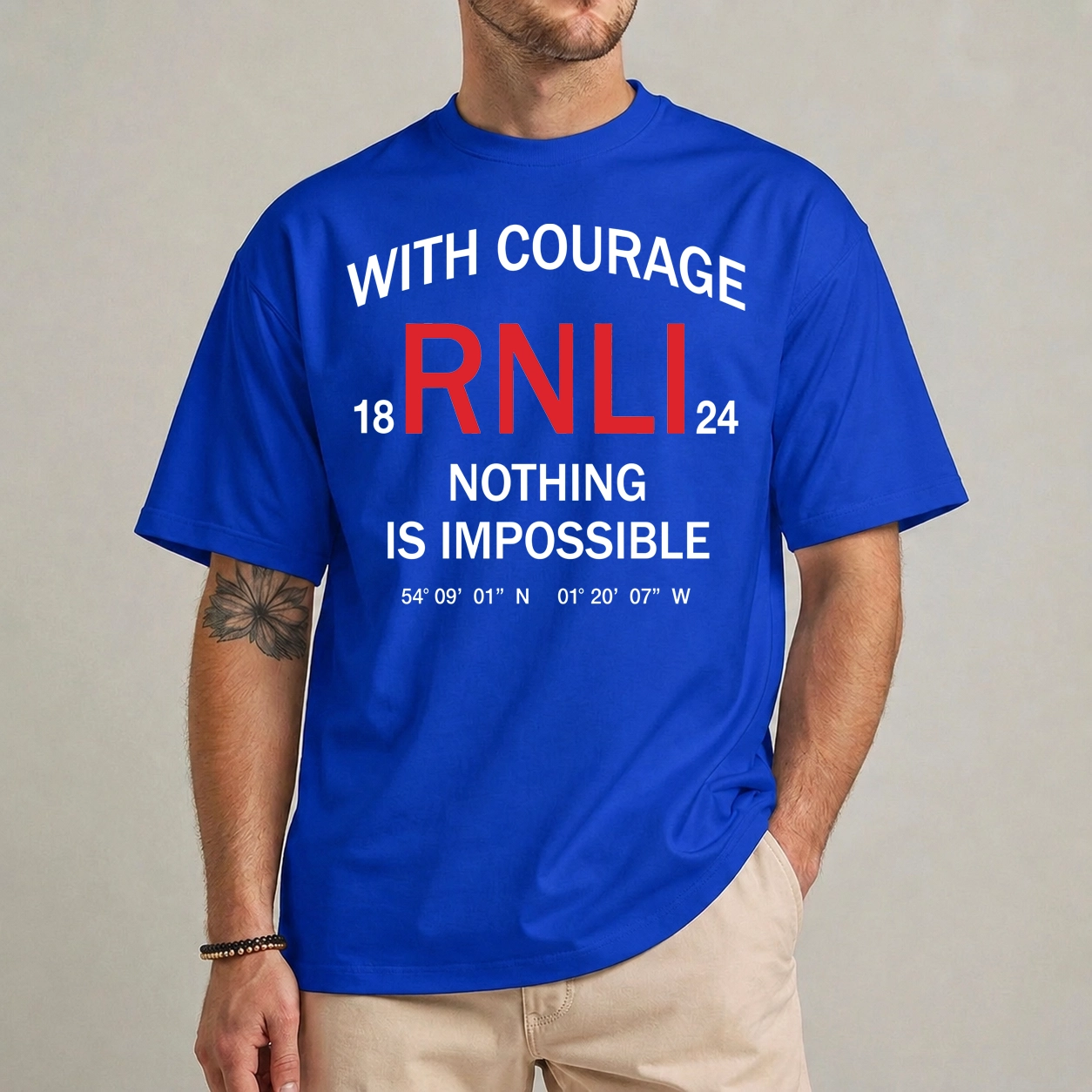 RNLI Courage Shirt | Nothing Is Impossible 1 Model wearing a blue RNLI courage shirt with red RNLI initials and white With Courage Nothing Is Impossible lettering