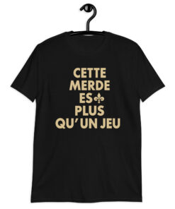 Cette Merde Est Plus Qu’un Jeu — black shirt with stacked gold French slogan lettering and a fleur-de-lis beside ES, front view